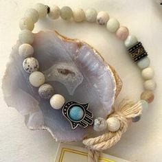 a bracelet with an evil eye on it and some other beads around it, sitting on top of a shell