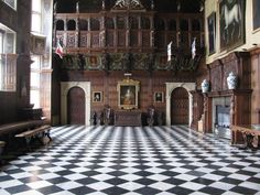 an ornate room with checkered floor and wooden paneled walls, painted in black and white