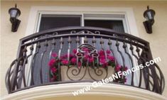 an iron balcony railing with pink flowers on the balconies and hanging from it