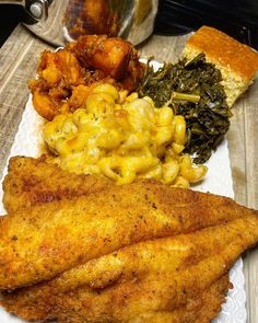 a white plate topped with fish, macaroni and cheese and other food items