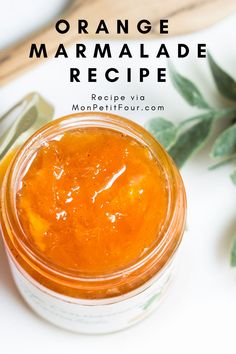 an orange marmalade recipe in a glass jar next to some leaves and spoons