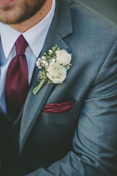 a man wearing a suit and tie with a boutonniere on his lapel