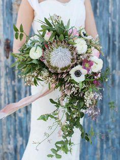 a woman holding a bouquet of flowers in her hand and wearing a white dress with pink accents