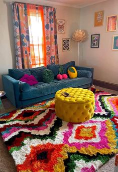 a brightly colored living room with colorful rugs on the floor and windows in the background