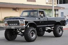 a large black truck driving down a street