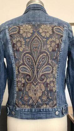 a denim jacket with an intricate design on the back