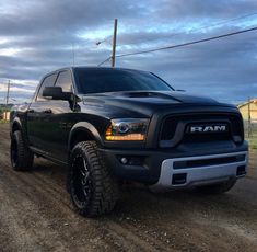 a black ram truck driving down a dirt road