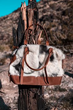 This handbag boasts a unique hair-on hide design on both sides, with patterned leather accents and bottom panel. The top closes with a zipper, and boasts two leather handles and a shoulder strap that is both adjustable and detachable. Size: 11"H x 17"W x 5"D Handle: 6" Brown Calf Hair Shoulder Bag With Leather Handles, Everyday Shoulder Bag With Leather Handles And Calf Hair, Everyday Calf Hair Shoulder Bag With Leather Handles, Brown Calf Hair Satchel Bags, Rectangular Calf Hair Bag With Leather Handles, Luxury Shoulder Bag With Leather Handles And Calf Hair, Luxury Calf Hair Satchel Bag, Brown Calf Hair Satchel Shoulder Bag, Calf Hair Shoulder Bag For Daily Use