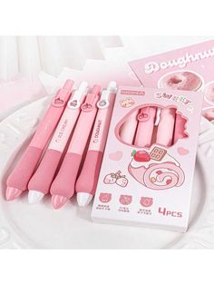 four pink pens sitting on top of a white plate next to a package of doughnuts