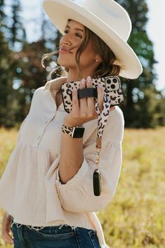 a woman wearing a white cowboy hat and holding up a cell phone in her right hand