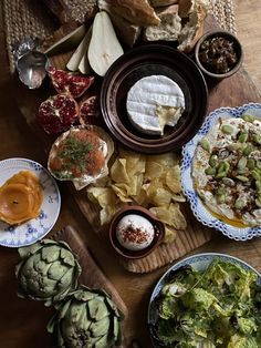 an assortment of food is laid out on a wooden table, including tortillas and artichokes