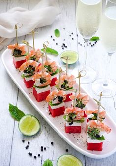 small appetizers are arranged on a plate with garnishes and limes