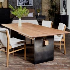 a wooden table with white chairs and a potted plant on it's end