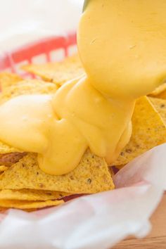 a person dipping cheese on top of tortilla chips