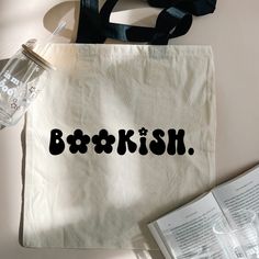 a tote bag with the word bookish on it next to an open book