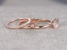 two rose gold wedding rings with white diamonds on the top and one pink diamond in the middle