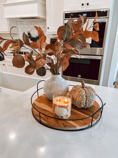 a kitchen counter top with a candle and some leaves on the tray in front of it