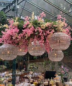 flowers are hanging from the ceiling in a garden center with chandeliers and tables