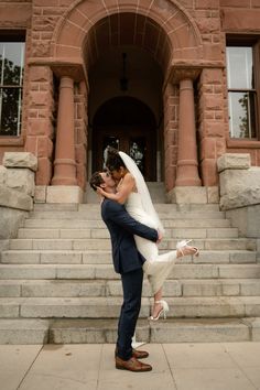 a bride and groom kissing on the steps