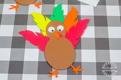 a turkey cut out on a checkered tablecloth next to some scissors and paper