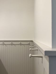 there is a row of coat hooks on the wall in this room with white walls