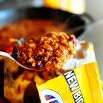 a spoon full of cereal on top of a table next to a bag of chips