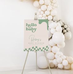 a baby shower sign surrounded by white balloons