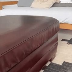 a large brown ottoman sitting in front of a bed