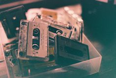 an old fashioned cassette player sitting on top of a table next to other vintage tapes