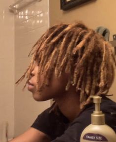 a man with dreadlocks sitting in front of a bathroom mirror