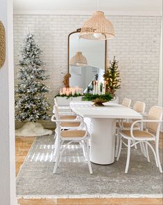 a dining room table with white chairs and christmas decorations