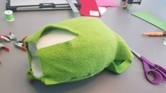 a green hat sitting on top of a table next to scissors and other crafting supplies