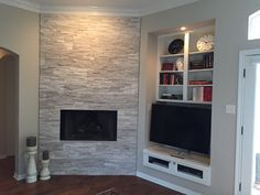 a living room with a fireplace and built in bookshelves next to a tv