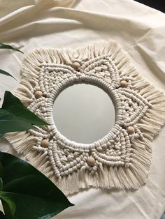 a white circular mirror sitting on top of a table next to a green leafy plant