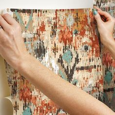 a woman is painting a rug on the wall with paint rollers and a brush