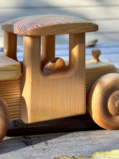 a wooden toy car with wheels and wood grain on the front, sitting on concrete