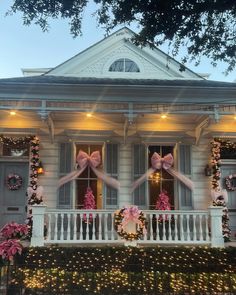 two pink bows on the front porch of a house decorated with christmas lights and wreaths