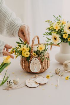 a person placing flowers in a basket on a table with tags and other items around it