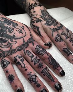 two hands with tattoos on them sitting on a white sheet and one has black ink all over it