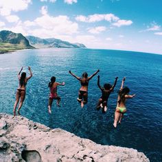 four women jumping into the water with their arms in the air