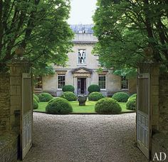 an entrance to a large house with trees and bushes on either side of the door