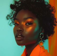 a woman with curly hair and bright makeup looks at the camera while wearing large hoop earrings