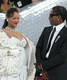 a man in a kilt standing next to a woman in a white dress and black suit