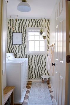 a washer and dryer in a small room with patterned wallpaper on the walls