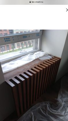 a wooden radiator sitting in front of a window next to a plastic sheet