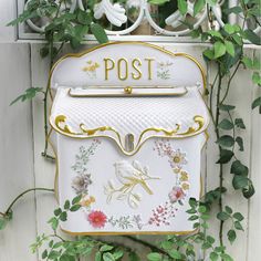 a white mailbox with flowers and vines around it