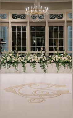 an ice rink with flowers and chandelier in front of two large windows at night