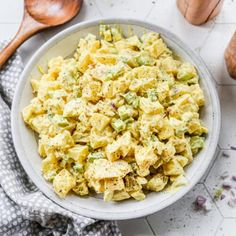 a white bowl filled with food next to wooden spoons