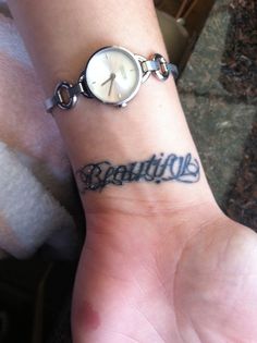 a person with a wrist tattoo that says beautiful on the wrist and is wearing a watch