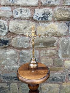 a small wooden table with a cross on it in front of a brick wall and floor